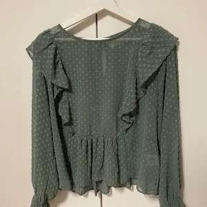 En mossgrön genomskinlig blus - Säljer en fin mossgrön prickig  genomskinlig blus. 