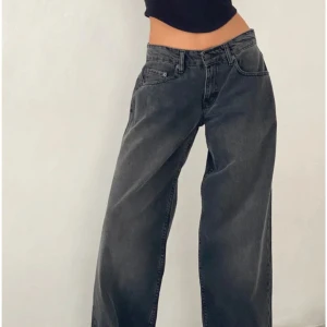 Svarta wide jeans - Snygga svarta wide jeans med låg midja. Perfekta för en avslappnad stil och kan matchas med olika toppar. De har en klassisk design med fickor och knappgylf.
