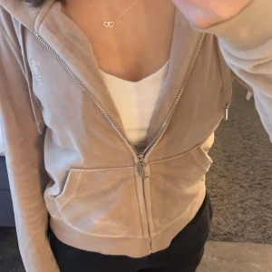 Juciy couture beige tröja - Säljer en beige Juciy couture tröja då den inte komme till andvändning så mycket. Bra skick men den har ett litet märke på under armen men de inget man tänker på när man har på sig den🩷