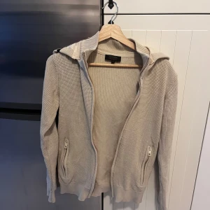 Beige stickad jacka från Woolrich - Säljer en snygg indcode jeans cardigan, bra skick och stilren i beige färg och en skön luva. Extremt eftertraktad och slutsåld överallt i alla storlekar. Storlek xs men skulle säga att den passar s.
