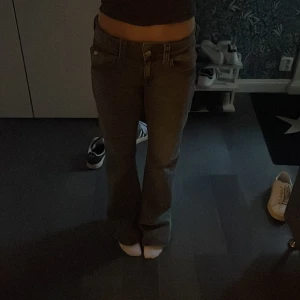 Grå bootcut jeans - Snygga grå bootcut jeans med låg midja. Perfekta för en avslappnad stil. Klassisk design med fem fickor och knappgylf.