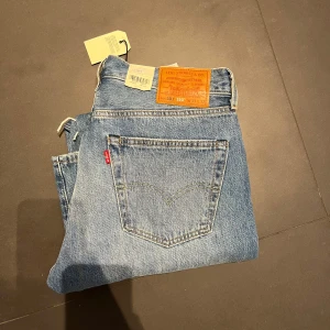Helt nya Levi's 501 Original Jeans - Klassiska Levi's 501 jeans i blå denim med slitna detaljer. Dessa jeans har en rak passform och är tillverkade av 100% bomull. Perfekta för en avslappnad stil med en vintage känsla.