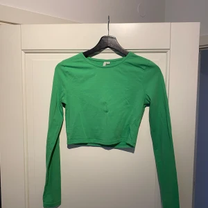 Grön croppad topp - Säljer en snygg grön croppad topp med långa ärmar. Perfekt för en trendig look. Toppen är i ett mjukt och bekvämt material.