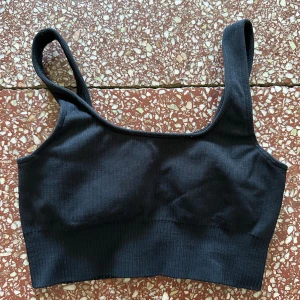 Svart ribbad linnetopp - Säljer en snygg svart ribbad sport bh. Materialet är mjukt och stretchigt, vilket gör den superbekväm att ha på sig. 