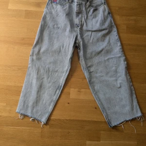 Gråa jeans med fransiga kanter - Säljer ett par ljusblå Big Boy jeans med fransiga kanter. De är i en loose fit och har en hög midja. Perfekta för skate stilen! Innermåttet på benen är 60 cm.