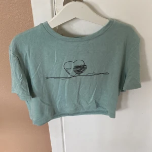 Ljusblå croppad t-shirt från Shein - Säljer en ljusblå croppad t-shirt från Shein. Den har ett tryck av ett hjärta och det står ”love”. T-shirten är kortärmad och gjord av bomull. Perfekt för en avslappnad sommarlook! Köparen betalar för frakt!