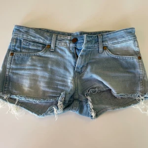 Lågmidjade jeans shorts - Lågmidjade jeansshorts från Wrangler köpta på plick. Säljer då de tyvärr inte passade mig, men annars är de supersnygga och i gott skick. Midjemått tvärs över: 38 cm