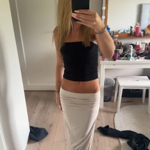 Beige långkjol - Säljer en snygg beige långkjol som är perfekt för både vardag och fest. Kjolen är tight och framhäver figuren på ett smickrande sätt. Den är gjord av ett mjukt och bekvämt material som känns skönt mot huden. Passar bra till en enkel topp eller en mer uppklädd outfit. Perfekt för sommaren eller våren!
