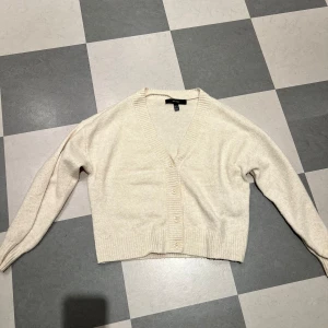Beige kofta från Vero Moda - Säljer en superfin beige kofta från Vero Moda i storlek XS. Den är stickad och har en v-ringad design med knappar framtill. Perfekt för höst och vinter, och den är i nyskick! 🧡