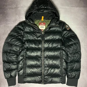 Svart dunjacka från Parajumpers - Snygg svart dunjacka från Parajumpers med huva och dragkedja. Jackan har en quiltad design och ribbade muddar vid ärmslut och nederkant. Perfekt för kyliga dagar.