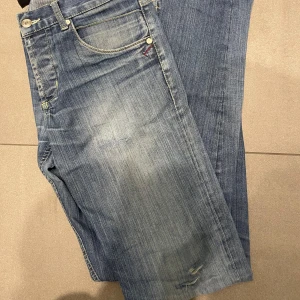 dondup george jeans - Snygga blå jeans med slitna detaljer och klassisk femficksdesign. De har en dragkedja och knapp framtill samt kontrastsömmar. Perfekta för en avslappnad stil. ett lätt hål där bak ( ej med i design) som knappt märks, kan sys igen