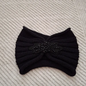 Svart stickat diadem med pärlor - Snyggt svart stickat diadem med dekorativa pärlor framtill. Perfekt för att hålla värmen och samtidigt se stilren ut. Passar bra till både vardag och festliga tillfällen.