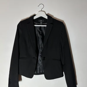 Randig kavaj - Snygg svart kavaj frän H&M med tunna vita ränder. Den ar croppad och har en klassisk krage med knappning framtill. Perfekt för en stilren look.🥰🥰🥰