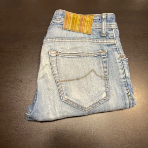 Jacob Cohën - Snygga ljusblå jeans från Jacob Cohen med slitna detaljer och knappgylf. De har en klassisk femficksdesign och är tillverkade i högkvalitativt denim. Perfekta för en avslappnad stil.