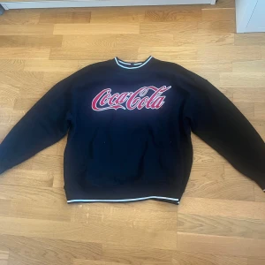 Svart sweatshirt från H&M x Coca-Cola - Säljer en svart sweatshirt från H&M med Coca-Cola tryck. Använd endast 2 gånger så är i toppskick!💕