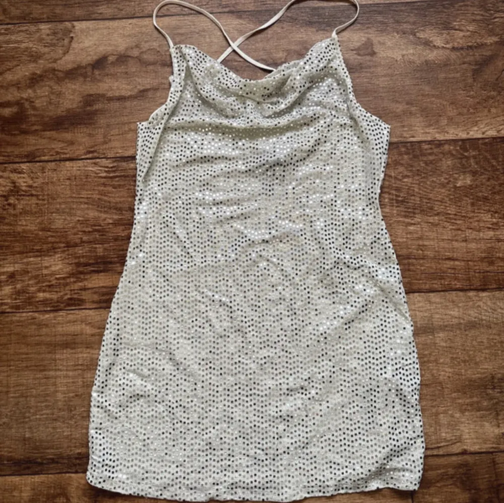 Glittrig mininklänning från H&M i storlek XS (kan även passa S). Den går ner i ryggen och banden bildar ett kors där bak🤩Skriv om du har några frågor!. Mekot.