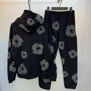 Denim Tear tracksuit  - Säljer en cool svart hoodie och byxa från Denim Tears med ett unikt grått blommönster. Hoodien har en klassisk passform med långa ärmar och en praktisk magficka. Perfekt för en avslappnad stil.
