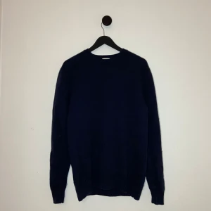 John Henric Cashmere Tröja - Säljer en stilren mörkblå tröja från John Henric i storlek M. Tröjan är tillverkad av 90% ull och 10% kashmir, vilket gör den både mjuk och varm. Perfekt för kyligare dagar med sin klassiska design och långa ärmar. Hör gärna av er vid flera frågor eller funderingar! 