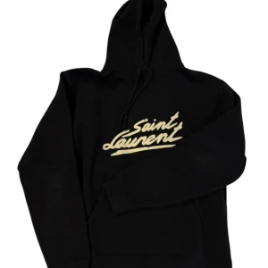  Saint Laurent hoodie  - Snygg svart hoodie från Saint Laurent med deras ikoniska logga i vitt på bröstet. Perfekt för en stilren och avslappnad look. Den har en klassisk huva med dragsko och långa ärmar. Säljer för den va för liten mvh scandicfashion 💯🙏🏽