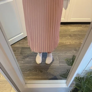 Rosa plisserad kjol - Säljer en söt rosa plisserad kjol i storlek S. Kjolen är tillverkad av 100% polyester och har en elastisk midja för extra komfort. Perfekt för en stilren och feminin look.