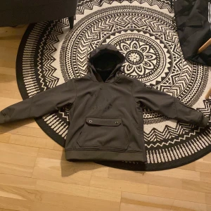 Svart hoodie från Slade - Säljer en stilren mörk grön hoodie från Slade med tryck på bröstet. Den har en praktisk ficka framtill och en bekväm huva. Perfekt för att åka med i skidbacken.