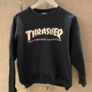 Svart sweatshirt från Thrasher - Säljer en svart sweatshirt från Thrasher med det ikoniska logotyptrycket i vitt på framsidan. Tröjan har långa ärmar och en rund halsringning. Perfekt för en avslappnad stil eller skate-session.