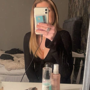 Svart knytblus - Snygg svart blus med knytning framtill. Blusen har långa ärmar och en djup v-ringning, perfekt för en trendig look. Passar bra till både jeans och kjol.
