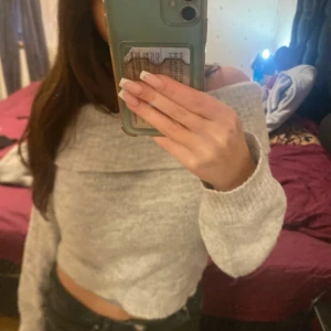 Grå offshoulder tröja - Säljer en snygg grå offshoulder tröja med croppad passform. Perfekt för en trendig look. Tröjan har långa ärmar och är tillverkad i ett mjukt material som ger en bekväm känsla. Passar utmärkt till både jeans och kjol.