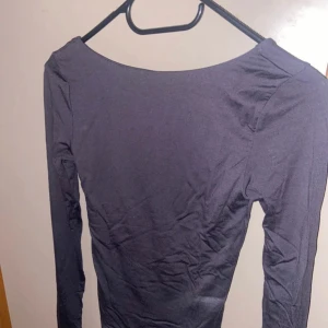 Grå långärmad topp - Säljer en grå långärmad tröja som är öppen i ryggen. Aldrig använt denna, då till och med prislappen sitter kvar! 