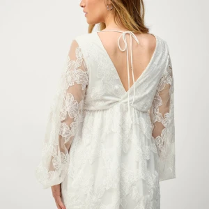 Vit spetsklänning med v-ringning - Charmig vit spetsklänning med v-ringning och långa ärmar. Klänningen har en öppen rygg med knytband och ett vackert blommigt mönster. Perfekt till studenten. Skriv för mer bilder eller frågor! Nypris:800