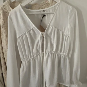 Vit blus från Aware - Säljer en vit blus från Aware med knytning framtill.  Org pris 449kr