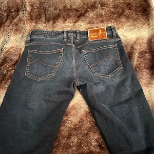 Mörkblå jeans från Jacob Cohen - Snygga mörkblå jeans från Jacob Cohen med klassisk femficksdesign och knappgylf. Tillverkade av utvalda japanska tyger med italienskt hantverk. Perfekta för en stilren look. Knappen längst upp saknas. Detta pågrund av pris 