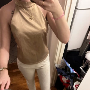 Beige halterneck topp från New Look - Snygg beige halterneck topp från New Look. Perfekt för en stilren look med sin ärmlösa design och mjuka material. Passar bra till både jeans och kjol.