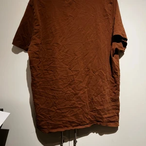 Brun t-shirt - Säljer en brun t-shirt med normal passform. Den är kortärmad och tillverkad i ett mjukt material. Perfekt för en avslappnad stil.