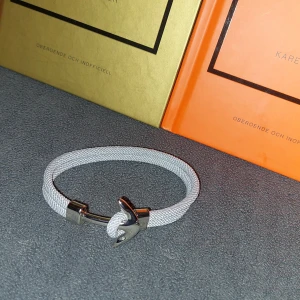 Grått Armband  - Snyggt grått armband med en unik ankardetalj i silverfärg. Armbandet är 19cm långt 