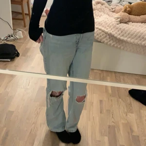 Ljusa jeans med slitningar - Säljer ett par ljusa jeans med slitningar. De har en straight passform och är perfekta för en avslappnad stil. Jeansen har en klassisk design med knappgylf. (jag är 175 och jeansen känns lite för korta för mitt gillande, därför säljs dom)