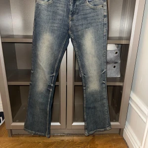Blå bootcut jeans - Snygga low waist  blå bootcut jeans med en klassisk tvätt. De har en bekväm passform och är perfekta för en avslappnad stil. Jeansen har fickor både fram och bak samt en knapp- och dragkedjestängning.