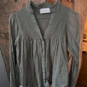 Neo noir blus - Jättefin Neo noir blus, i färgen smoke green. Inköpt på Åhlens för 749:- förra året. Storlek 34. Blusen har en luftig och smickrande modell som passar toppen i vår/sommar. Den är sparsamt använd, inga defekter alls. 