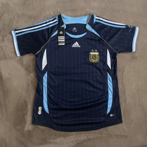 Helt ny Argentina Retro Fotbollströja 2006/07 - Oanvänd Marinblå Argentina Retro Fotbollströja från 2006/07 säsongen. Strlk M. Inkluderar tagsen som klipptes av innan den testades. Vid fler frågor eller funderingar, skriv pm. Mvh