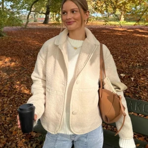 Beige teddyjacka från Nelly - Mysig beige teddyjacka från Nelly med knappar framtill. Jackan har en klassisk krage och långa ärmar, perfekt för kyliga höstdagar. Den är använd endast 1 gång💕