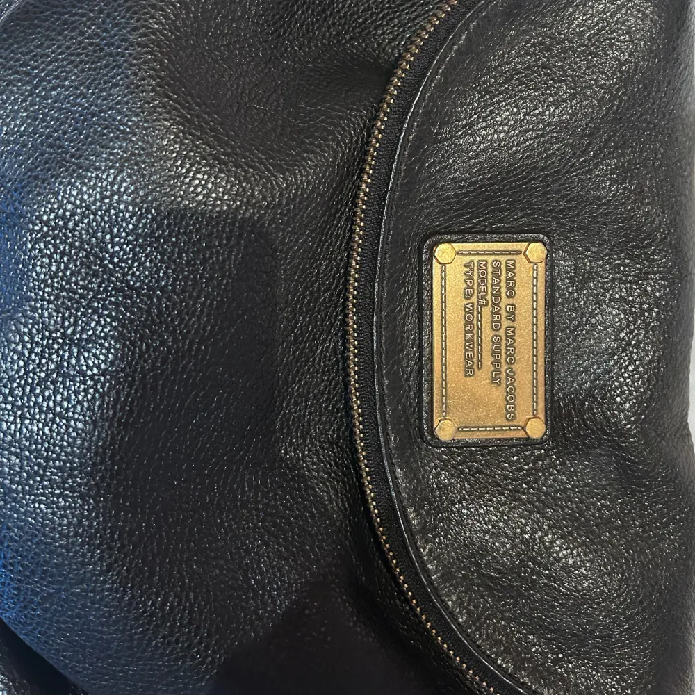 Säljer en snygg svart axelväska i skinn från Marc by Marc Jacobs. Väskan har en praktisk dragkedja och en stilren design med en logotypplatta på framsidan. Insidan är fodrad med ett coolt mönster. Perfekt för både vardag och fest!. Laukut & Käsilaukut.