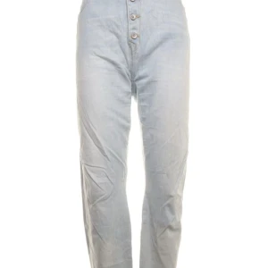 Ljusblå jeans från Lindex - Säljer ett par ljusblå jeans från Lindex i bra skick. De är högmidjade med knappar framtill och tillverkade av 99% bomull och 1% elastan för en bekväm passform. Perfekta för både vardag och fest!