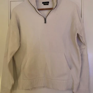 Vit tröja med dragkedja från Massimo Dutti - Säljer en stilren vit tröja från Massimo Dutti i mycket bra skick. Den har en halv dragkedja och en bekväm passform med ribbade muddar. Perfekt för både höst och vinter. Passar lika bra till vardags som till lite finare tillfällen.