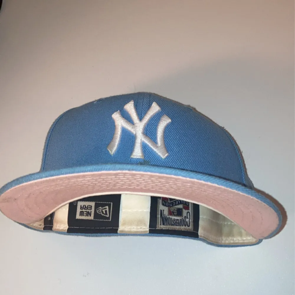 Säljer en snygg pastel blå New Era keps fitted med vit broderad logga framtill.                Kepsen har en rosa underskärm och ett 1999 All-Star patch på sidan. Storleken är 7 /14, 57,7cm. Priset kan förhandlas . Accessoarer.