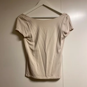 Beige topp från Gina Tricot - Säljer en stilren beige topp från Gina Tricot i storlek M. Toppen har korta ärmar och en djup öppen rygg, perfekt för sommardagar eller en utekväll. Materialet känns mjukt och bekvämt mot huden. Passar både till vardags och fest! Använd Max 2 gånger!
