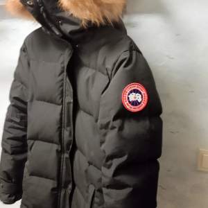 Säljer en svart dunjacka från Canada Goose  Jackan har en varm pälsdetalj på huvan och en praktisk dragkedja framtill. Perfekt för kalla vinterdagar! 🖤 Ena fick dragkedjan är sönder som de syns på en bild därav priset samt skulle behövas tvättas men annars fin o varm  storlek S/P