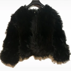 Fluffig Syntet päls kappa - Svart päls imitation jacka med dragkedja Normal i storleken :S/M och sitter kort Glansigt innertyg, inte fodrad så passar nu till hösten  Väldigt gott skick utan några tydliga defekter små tecken på användning  Sparsamt använt och välskött  