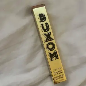 Säljer en Buxom Full-On Plumping Lip Polish i en snygg guldig förpackning. Denna läppglans ger en fyllig och glansig look med en plumpande effekt. Perfekt för att ge läpparna extra volym och glans. Förpackningen är elegant och lätt att ta med sig i väskan.