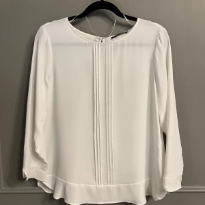 Esprit Blus Vit - Vit blus från Esprit. Knappt använd. Strl 44. Mindre fläck längst ned som syns på bild 4, har ej testat att försöka få bort den.