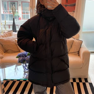 Svart dunjacka från Rocky - Säljer en svart dunjacka från Rocky. Jackan är perfekt för vintern med sitt varma dunfoder och långa ärmar. Den har en dragkedja framtill och en hög krage för extra skydd mot kylan. 70% dunfyllning och 30% fjäder. Med avtagbar luva